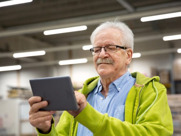 Keski-ikäinen mies selaa tablettitietokonetta.