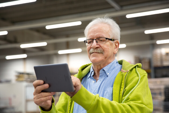 Keski-ikäinen mies selaa tablettitietokonetta.